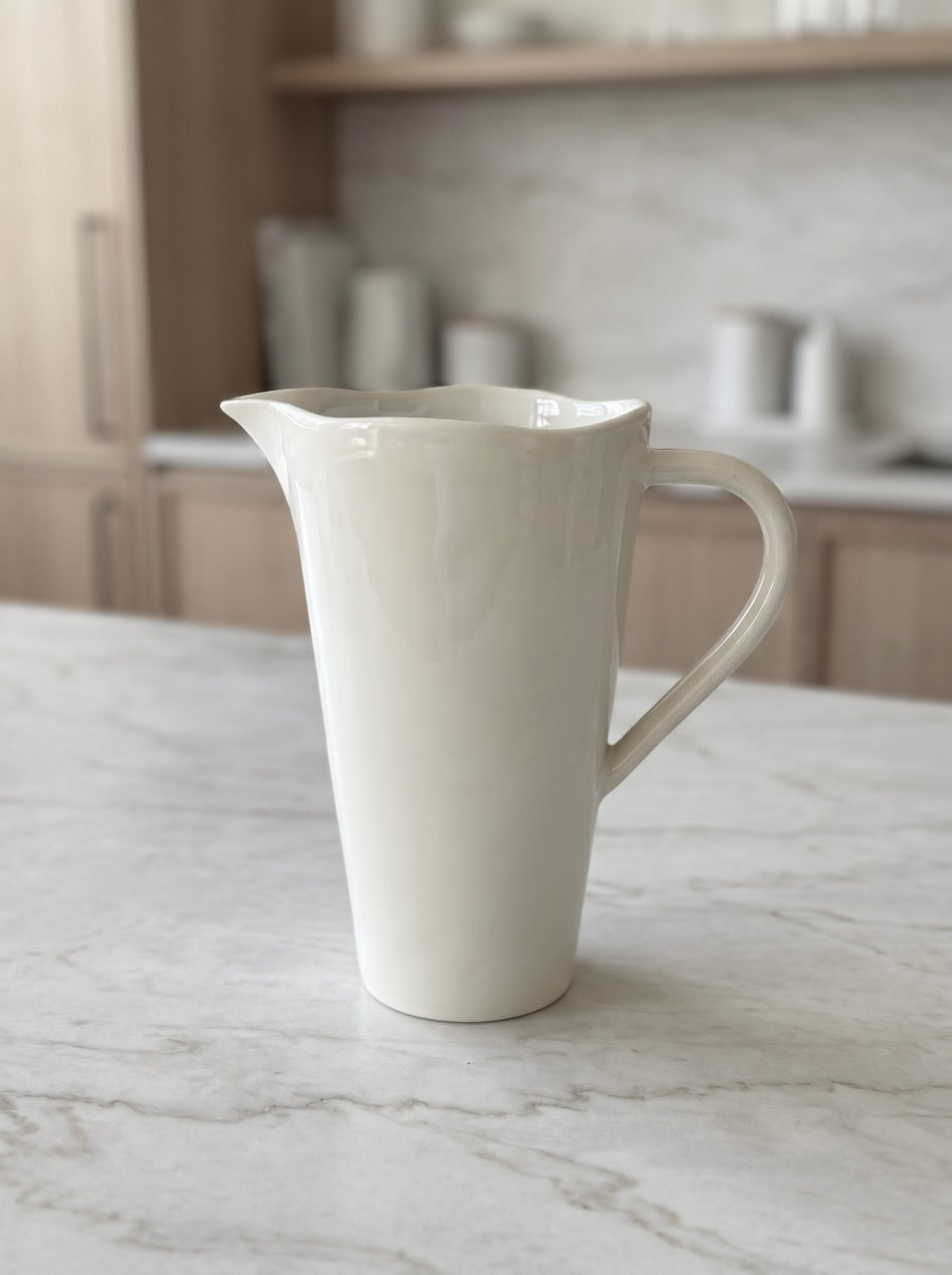 White ceramic jug on a marble surface with a kitchen background
