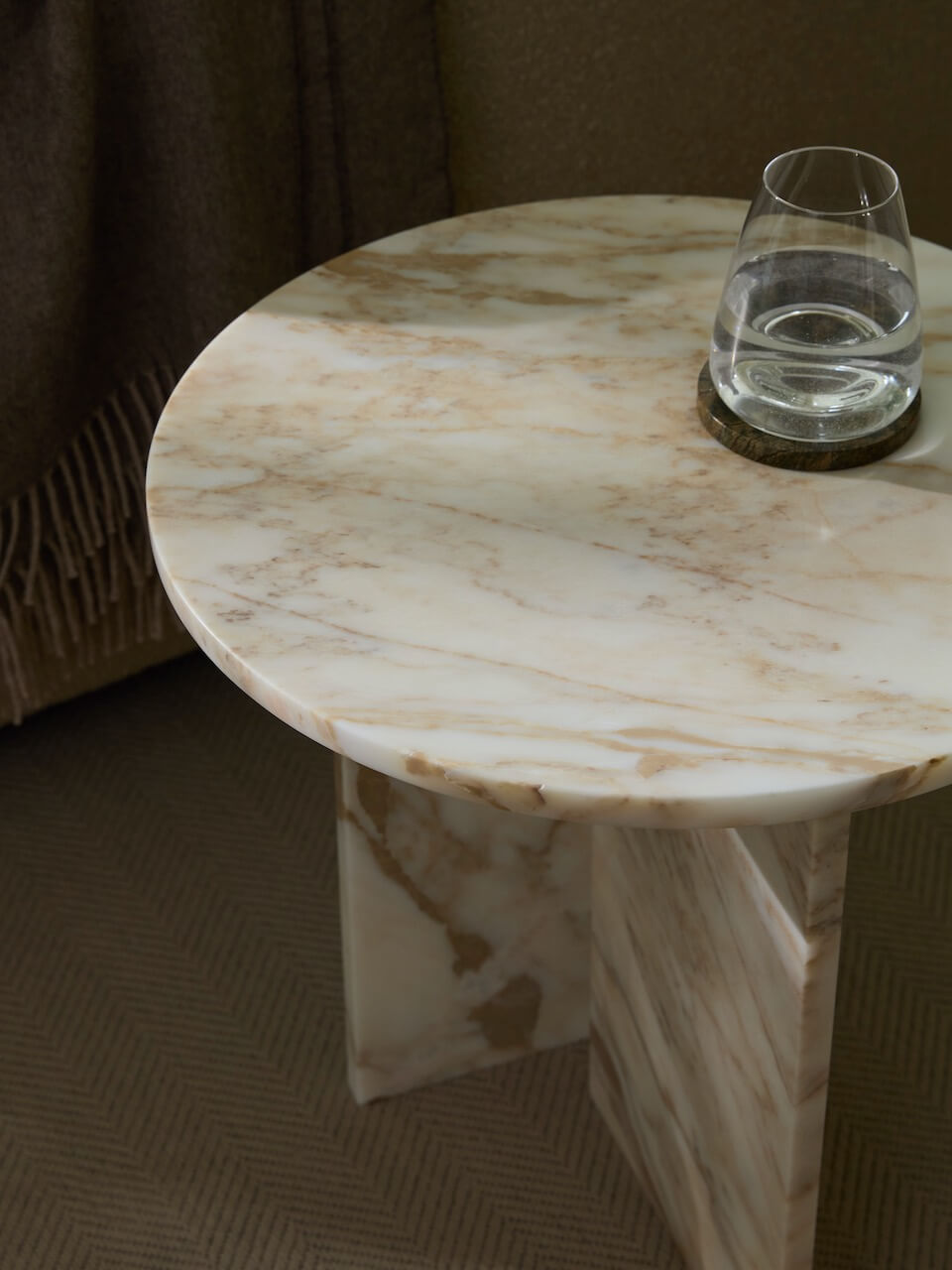 Round marble table with a glass on a brown textured surface