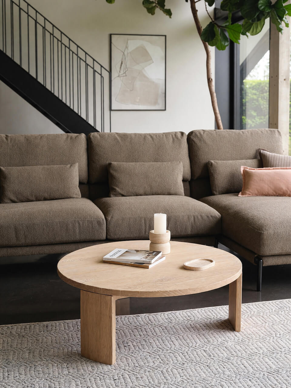 Modern living room with a sectional sofa and round wooden coffee table.