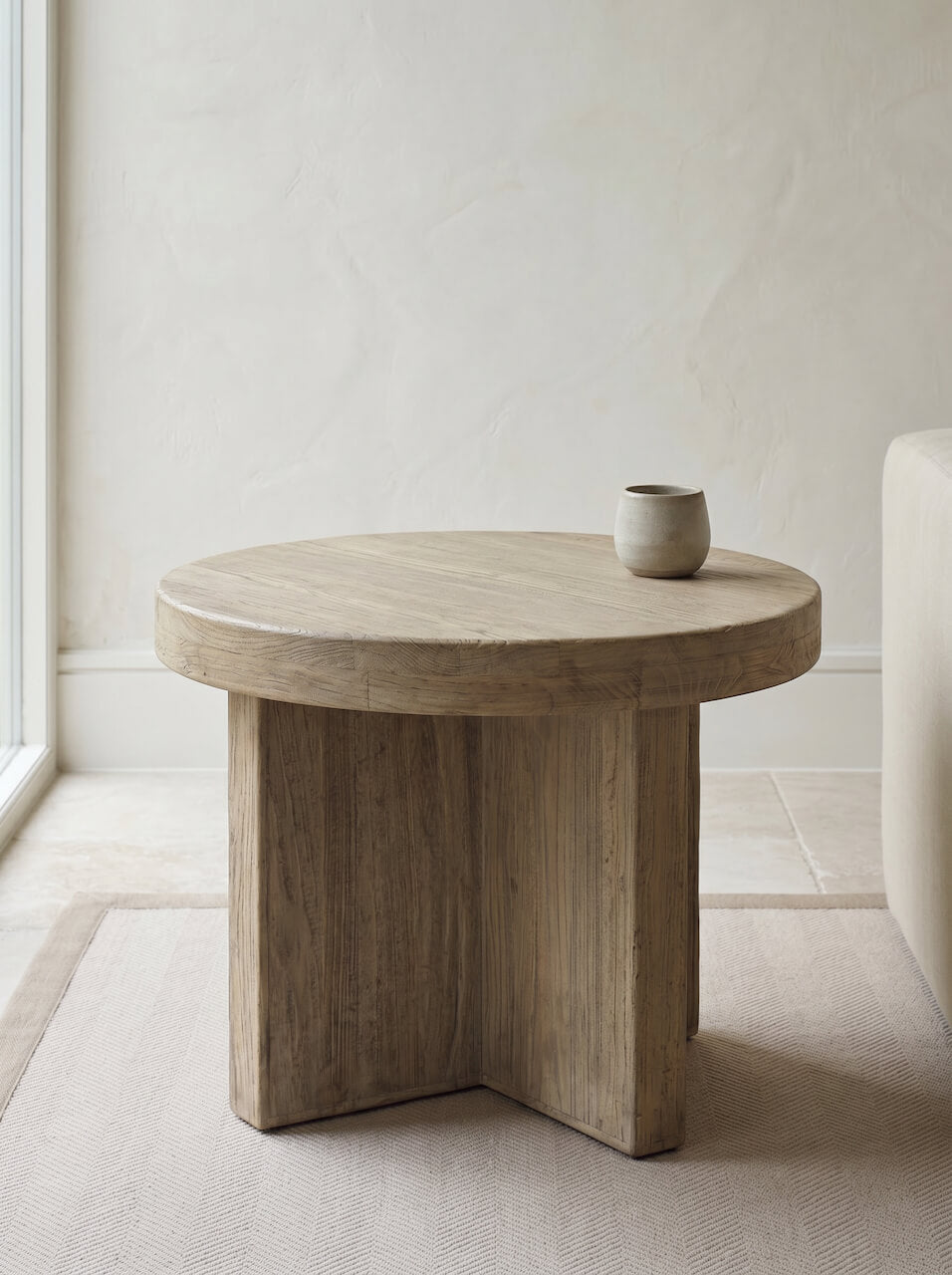Round solid wood side table in a contemporary neutral living room