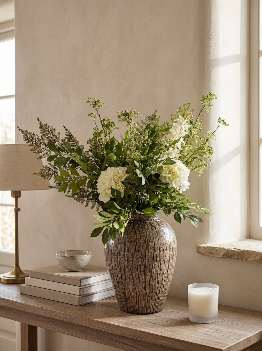 Decorative vase with flowers on a wooden table in a bright room