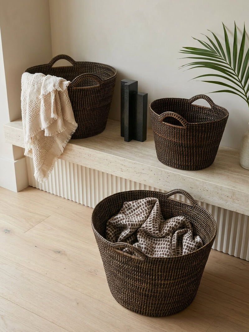 Nairn brown rattan bucket basket collection in medium, large and extra large styled with throws on stone bench in neutral interior