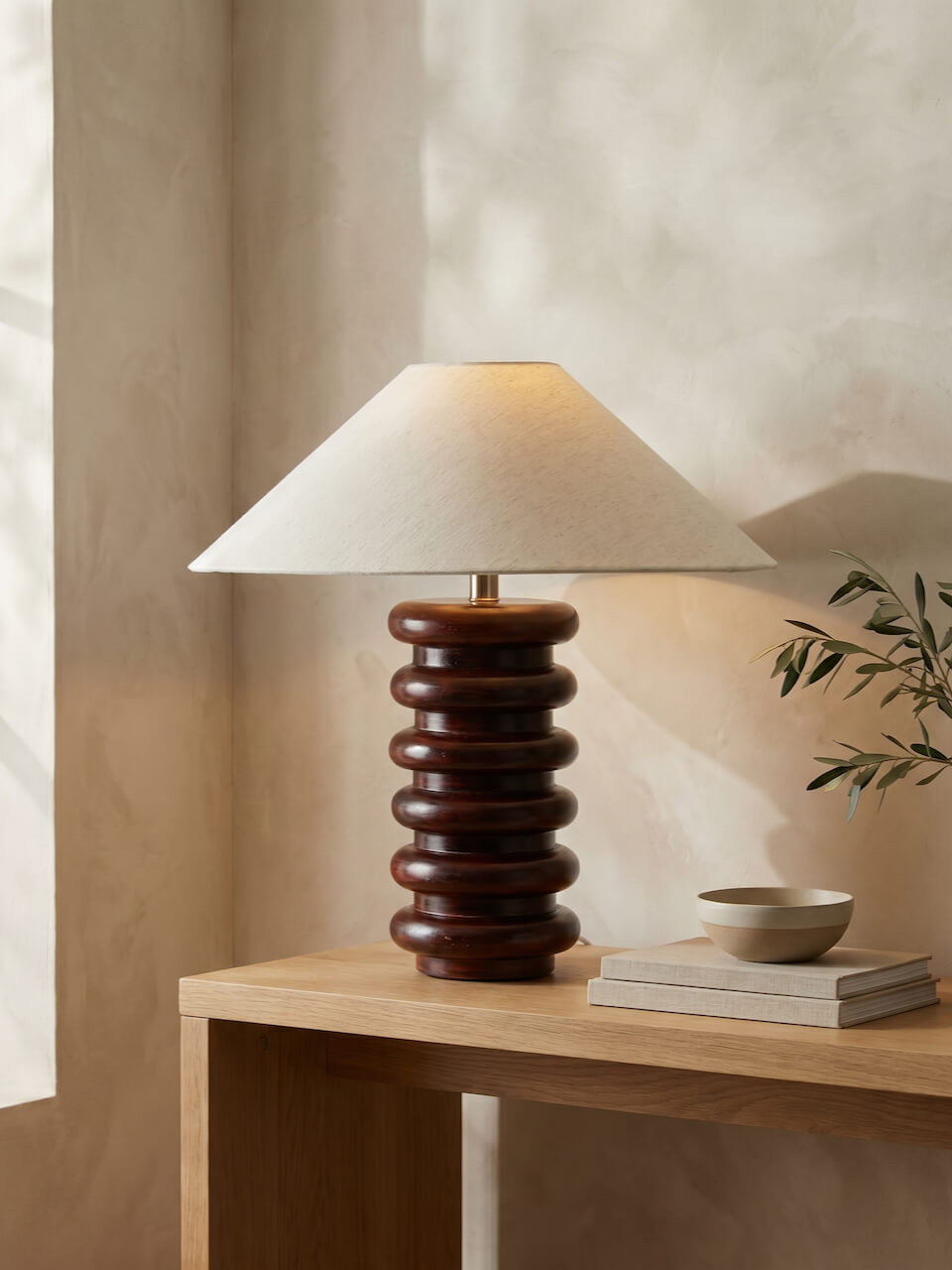 Table lamp with a wooden base and white shade on a wooden table.