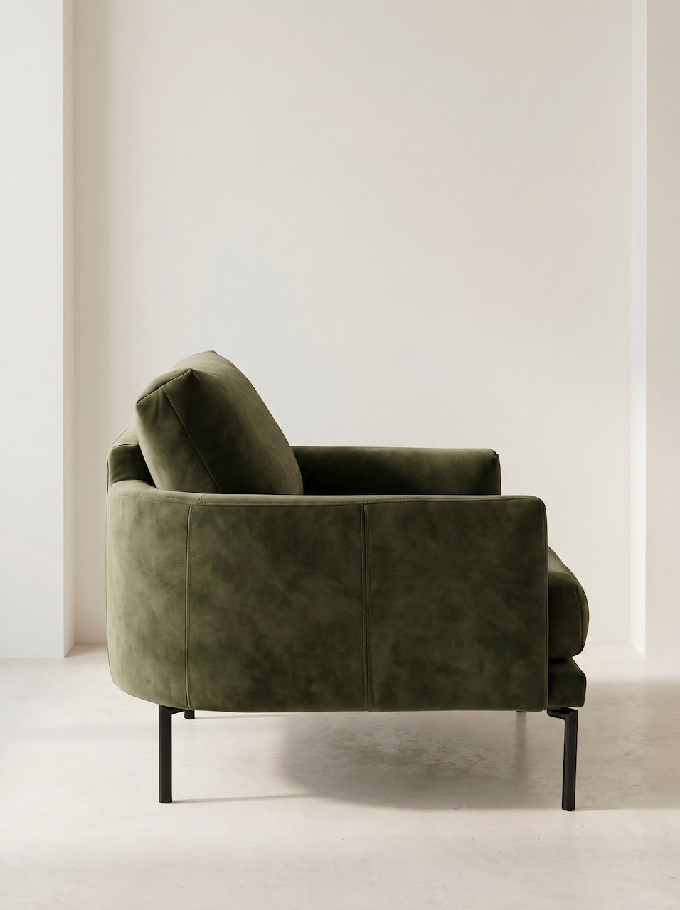 Green armchair in a minimalistic room with white walls and floor.